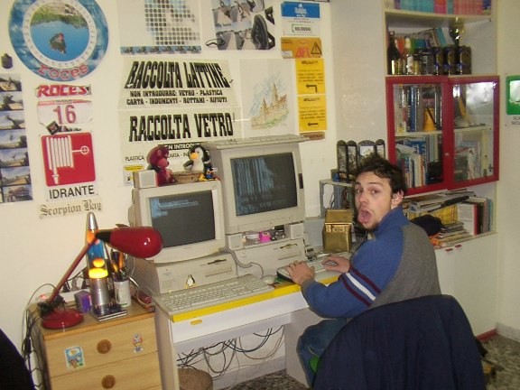 My workstation, circa 2001 — two PowerMacs (7200 with Yellow Dog Linux, 7300 with NetBSD), two CRT monitors, red desk lamp, Italian recycling signs on the wall (RACCOLTA LATTINE, RACCOLTA VETRO). This is where the IPv6 patches were written.